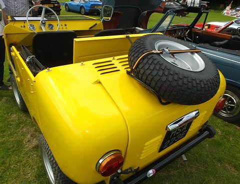 Yellow open miniature off-roader seen from above at the rear, a spare wheel on the engine lid and British plates.