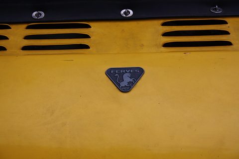 Mustard-yellow panel with two rows of black cooling louvres above a small triangular badge showing a leaping bull. Opens a larger view