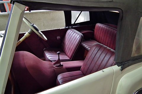 Cream body side cut open to show pleated maroon front and rear seats under a grey hood. Opens a larger view