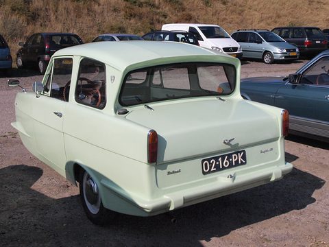 Pale green three-wheel saloon with a reverse-rake rear window, parked cars behind. Opens a larger view