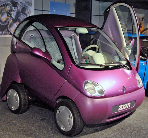 Purple bubble-shaped two-seat concept with gullwing doors raised and a ‘zoom’ badge, on a museum floor.
