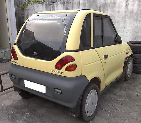 Rear of a pale-yellow microcar with grey lower panels, round tail lamps and a white blanked plate. Opens a larger view