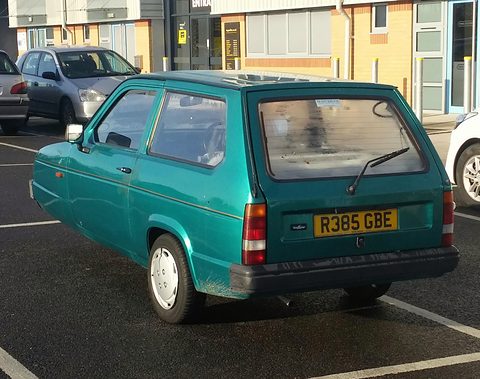 Green hatchback from the rear quarter showing its tailgate, rear wiper and yellow number plate. Opens a larger view