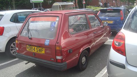 Maroon three-wheeled estate seen from behind in a crowded car park. Opens a larger view