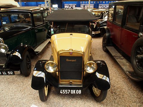 The front of a small yellow car: a narrow radiator with a Rosengart badge, two headlamps, black wings and a number plate. Opens a larger view
