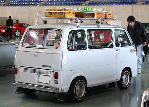 Rear of a white small van with engine grille louvres, a ‘360’ badge and a loaded roof rack. Opens a larger view