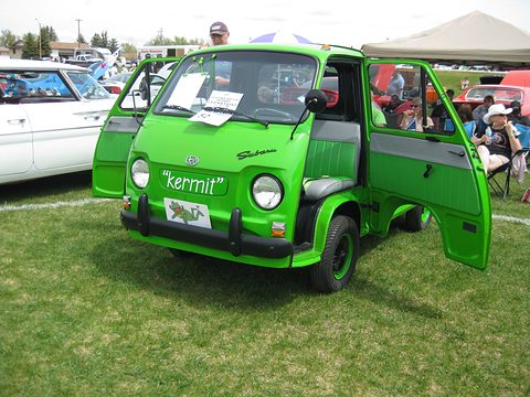Bright green small cab-over pick-up with both doors open on grass at a car show. Opens a larger view