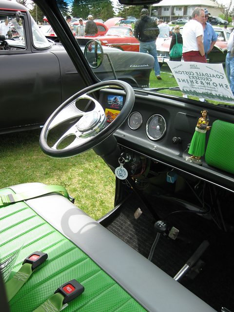 Inside a small cab: a thin white steering wheel, simple gauges and a long gear lever. Opens a larger view