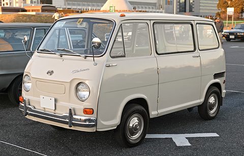 Cream small cab-over van with chrome bumpers and round headlamps in a car park. Opens a larger view