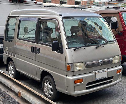 Silver high-roof small van parked beside a guard rail with other vans behind. Opens a larger view