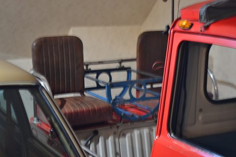 Two brown vinyl seats and a blue rack in the open back of a small red truck. Opens a larger view
