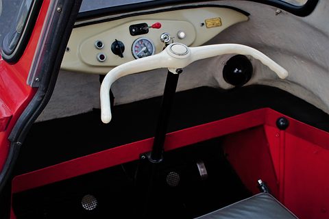 Cream handlebar on a column in front of a cream dashboard with a speedometer and switches