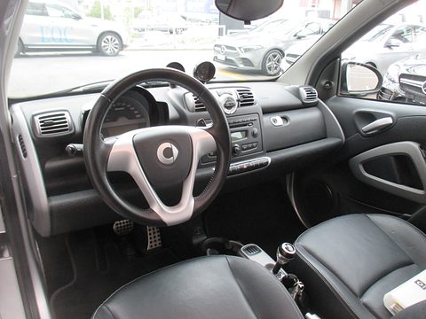 Black dashboard with three-spoke Brabus steering wheel, round vents, radio and black leather seats. Opens a larger view