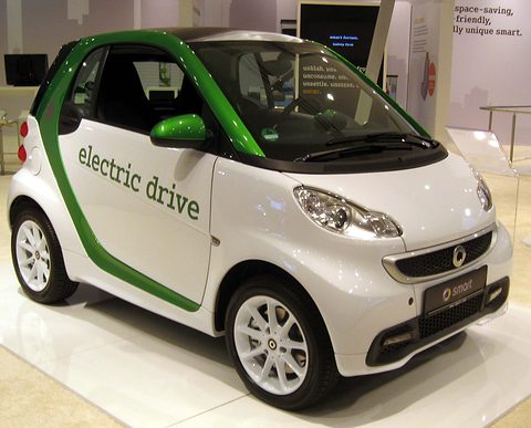 White two-seater with a green safety cell and ‘electric drive’ lettering on a white show stand.