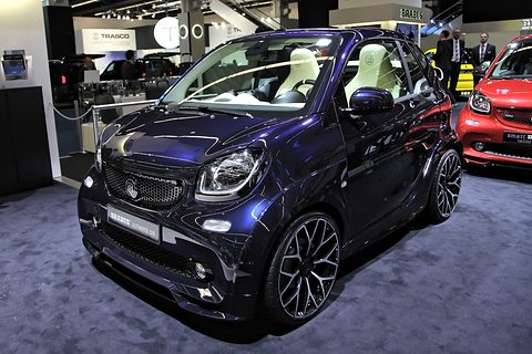 Dark blue convertible two-seater with cream seats and large black alloy wheels on a show-stand carpet. Opens a larger view