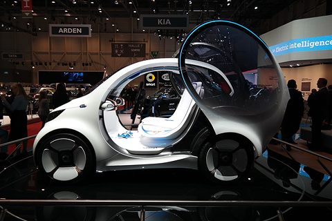 White and grey bubble-like two-seat concept with a huge transparent door raised, visitors around it. Opens a larger view
