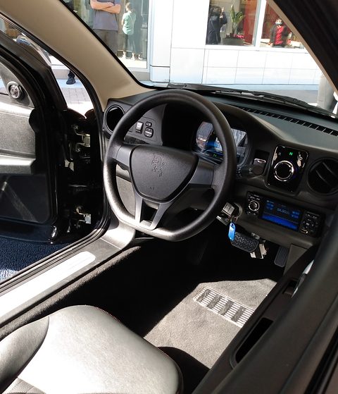Black steering wheel, a digital instrument binnacle, a centre screen and a light grey seat.