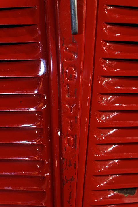 Close view of glossy red pressed-steel louvres either side of a central strip carrying the raised word Solyto. Opens a larger view
