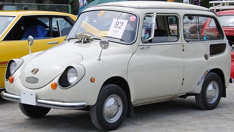 Cream small three-door estate with a rounded Subaru 360 nose and a long flat roof, a number card in the windscreen. Opens a larger view