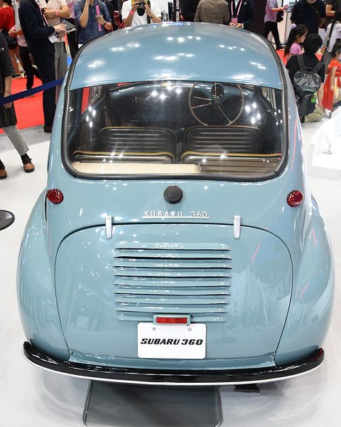 Rear view of a grey-blue rounded car with a horizontal-louvred engine lid, SUBARU 360 script and a plate. Opens a larger view