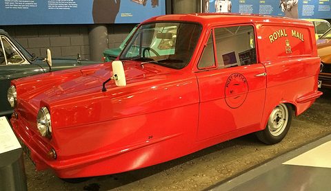 Red three-wheeled van side-on with a post-horn roundel on the door and Royal Mail lettering. Opens a larger view