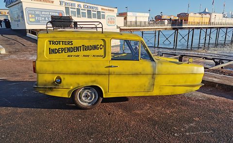 Yellow signwritten van side-on on a seafront, a pier and a fish-and-chip shop behind. Opens a larger view