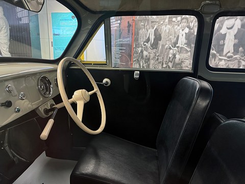 Black vinyl front seats, a cream steering wheel and a cream dashboard, a black-and-white photograph mural through the windows. Opens a larger view