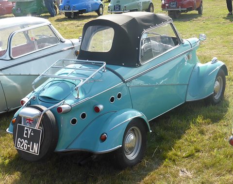 Rear quarter of a turquoise soft-top bubble car with a luggage rack, spare wheel and French plate on its tail. Opens a larger view