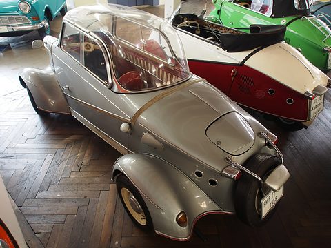 High rear view of a silver bubble car with round cooling holes and a tail-mounted spare wheel. Opens a larger view