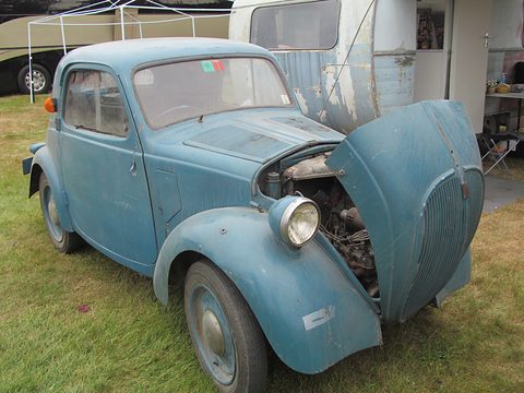 Faded blue small saloon with its bonnet tipped open showing the engine ahead of the front wheels. Opens a larger view
