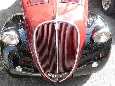 Narrow vertical-slatted red grille between two headlamps on glossy black wings, plate WSU 838 below. Opens a larger view