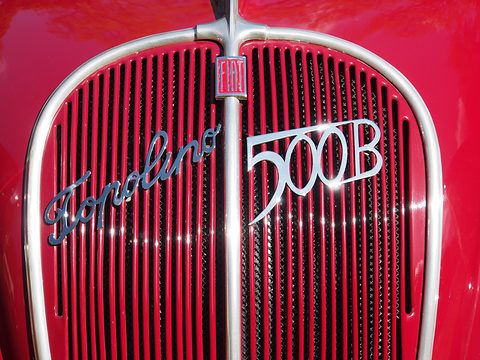 Chrome Topolino and 500B scripts and a FIAT badge on a red slatted grille. Opens a larger view