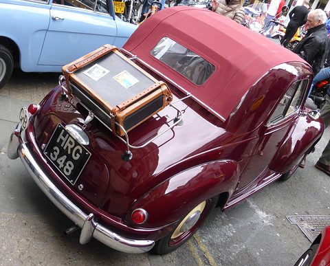 Maroon small car from the left rear, plate HRG 348, a leather case on a tail rack and the roof folded. Opens a larger view