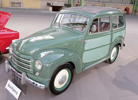 Green small estate with lighter green side panels on a grey floor, a red car beside it. Opens a larger view