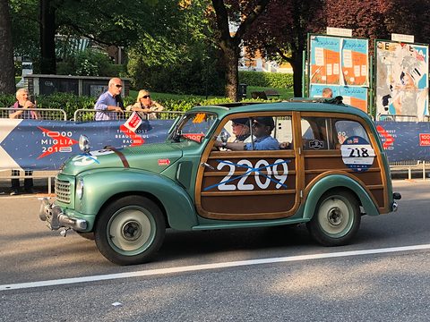 Green small estate with wood-look side panels and big 2209 numbers, its crew aboard, spectators behind. Opens a larger view