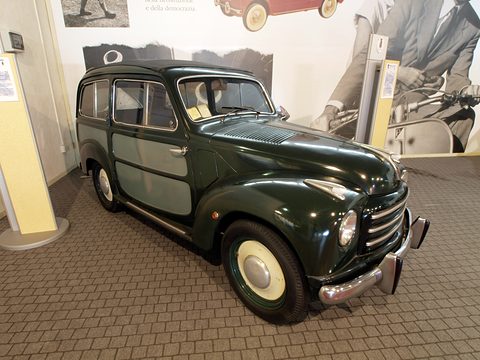 Dark green small estate with darker side panels from the right front in a museum. Opens a larger view