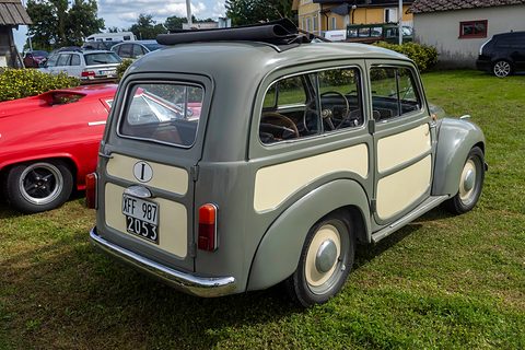 Grey small estate with cream panels from the left rear, a Swedish plate and a red car beside it. Opens a larger view