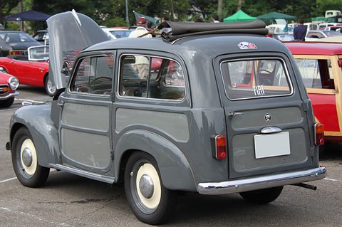 Grey small estate with darker panels from the left rear, its roof rolled back and the plate blanked. Opens a larger view