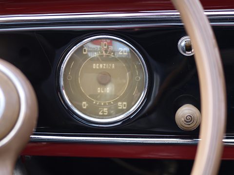 Round cream gauge marked BENZINA and OLIO on a black dashboard, the steering wheel rim in front. Opens a larger view