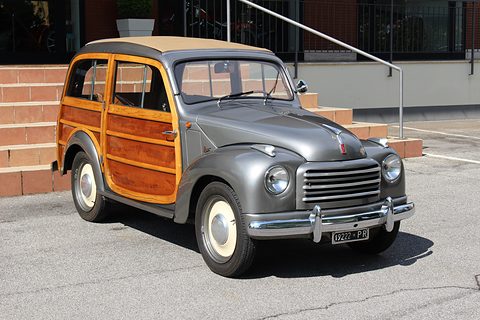Grey small estate with varnished wood panels and a horizontal-bar grille, parked on tarmac. Opens a larger view