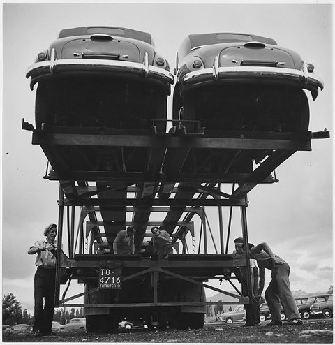 Black and white: two small saloons on the upper deck of a transporter, workmen below. Opens a larger view