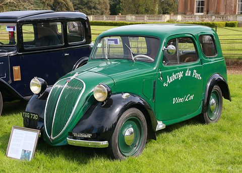 Green small van with black wings and gold lettering parked on a lawn before a country house. Opens a larger view