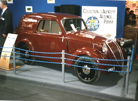 Brown small van behind a rope barrier on a display stand, a collection sign behind. Opens a larger view