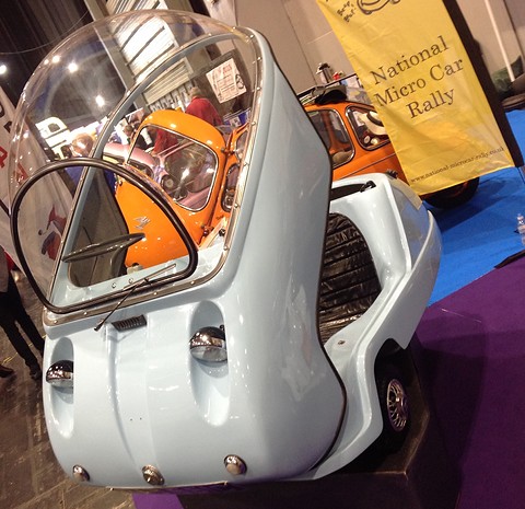 Pale blue bubble car with its dome and front panel hinged up, the seat visible inside. Opens a larger view