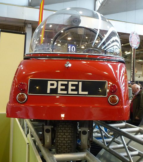 Red bubble car from behind on a display ramp, a PEEL number plate on its tail. Opens a larger view