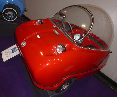 Glossy red bubble car seen from above at the front quarter, its clear dome closed. Opens a larger view