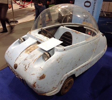 Battered pale blue bubble car with flaking paint and a rusty headlamp rim, a note on its bonnet. Opens a larger view