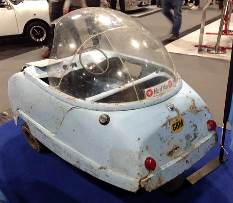 Weathered pale blue bubble car with chipped paint and a scratched dome on a blue plinth. Opens a larger view
