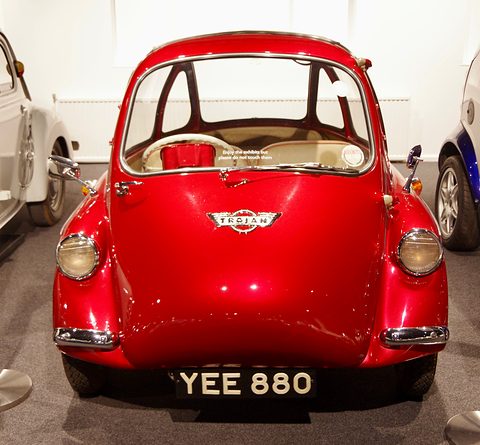 Red bubble car seen from the front with a chrome Trojan badge on its door. Opens a larger view