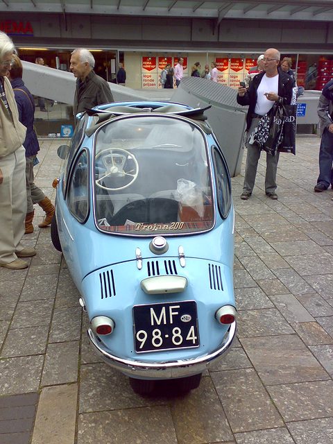 Pale blue bubble car seen from directly behind in a pedestrian street, people around. Opens a larger view